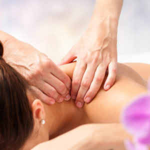 Macro close up of hands massaging female neck and shoulders.