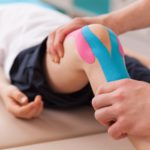 Physiotherapist doing with child exercise for knee